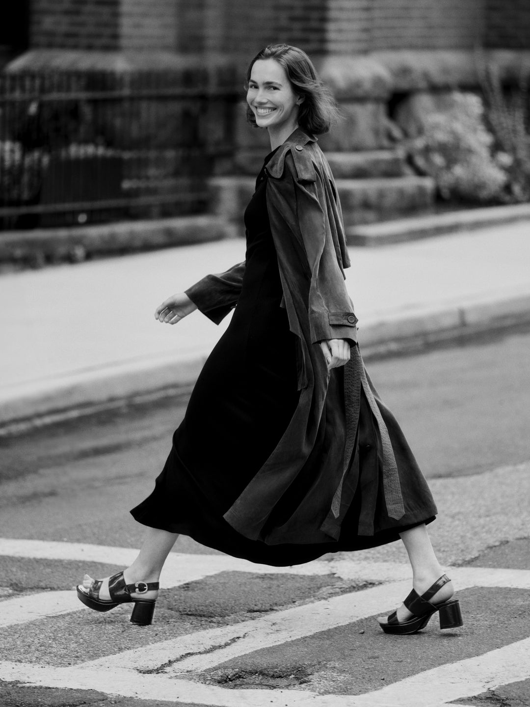 Woman in a long coat crossing a street wearing camera platform heel